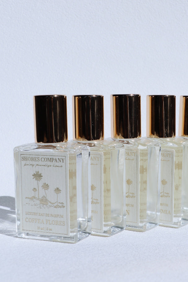 Row of perfume bottles with gold caps on a white background