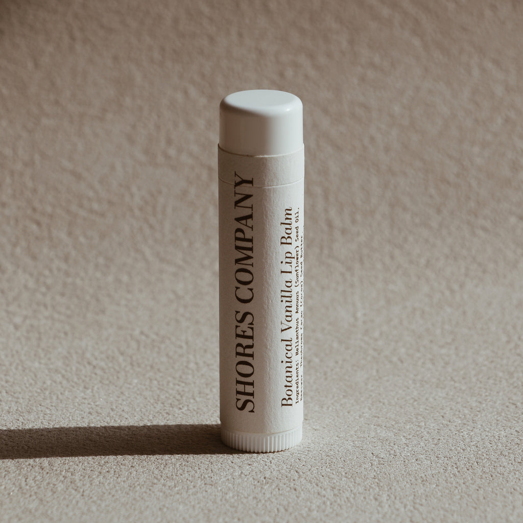 Lip balm tube with 'Shores Company' branding on a beige background