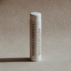 Lip balm tube with 'Shores Company' branding on a beige background