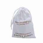 Elegant bottle of Coffea Flores Eau de Parfum in linen dust bag. A refreshing, island-inspired fragrance perfect for daily wear, capturing the essence of sunlit mornings and vibrant island life.