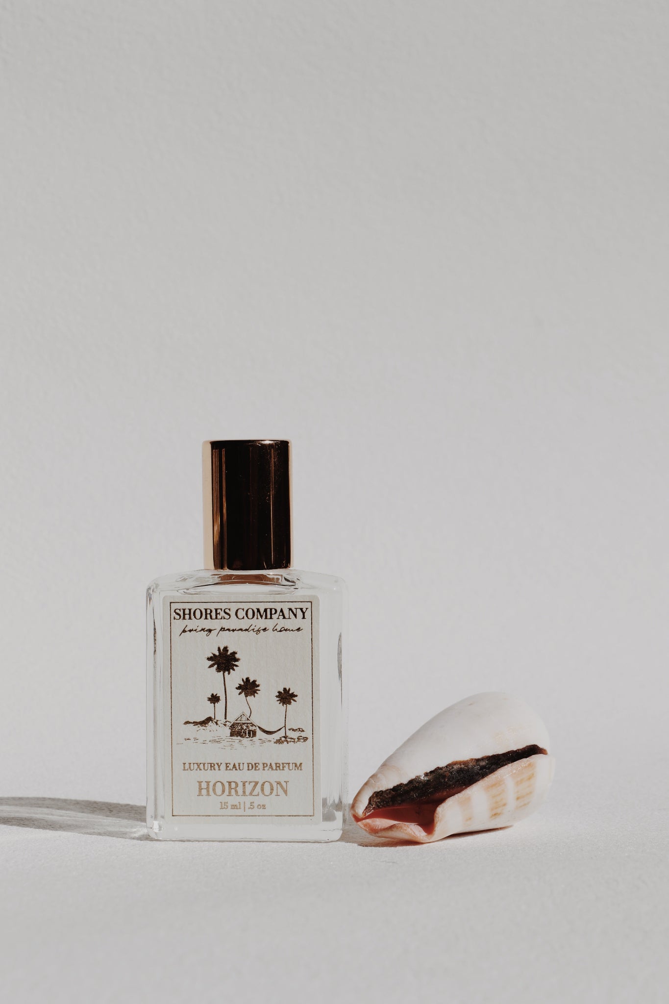 Shores & Company perfume bottle with a seashell on a light gray background