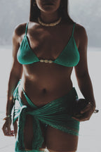 Model wearing a turquoise  bikini and sarong on a beach