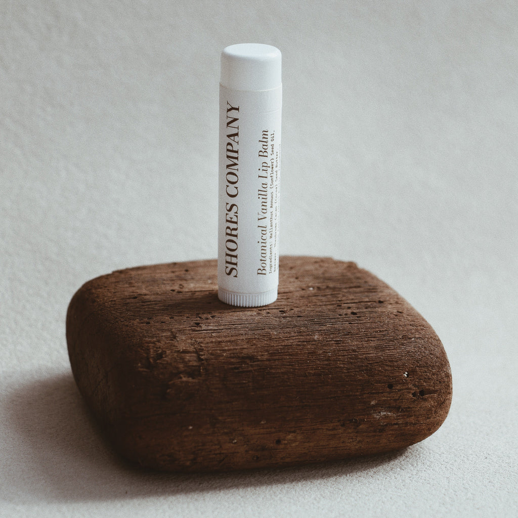 Shores Co lip balm tube on a wooden block with a neutral background