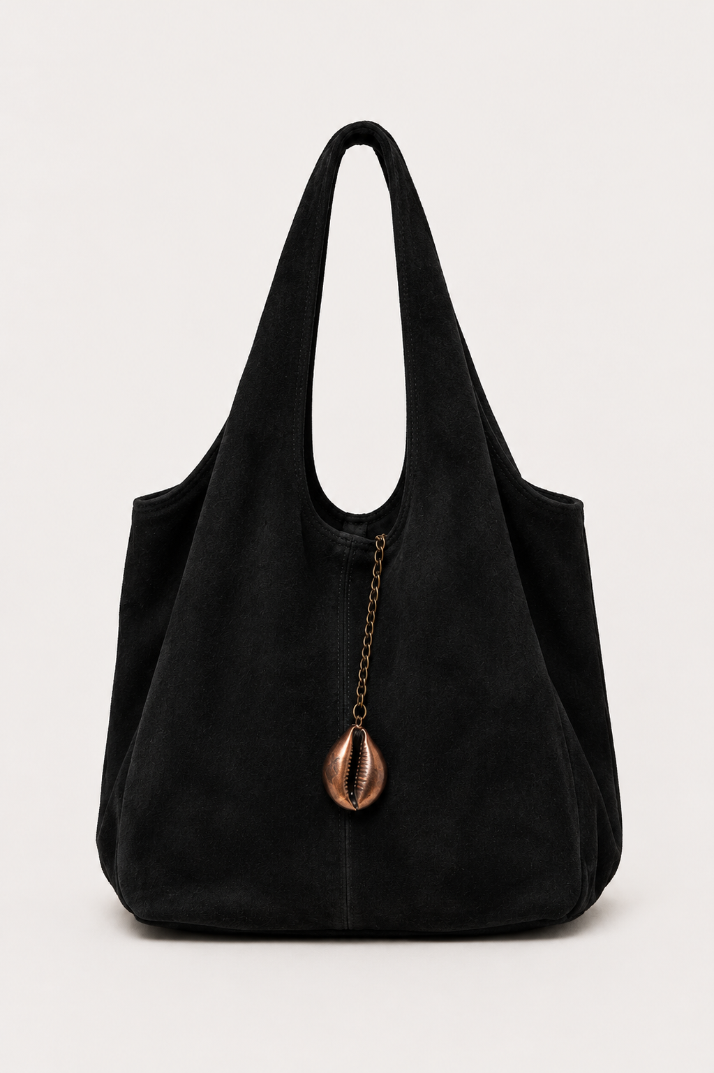 A black suede hobo shoulder bag with a decorative bronze cowrie shell charm hanging from a chain zipper, set against a plain light gray background.