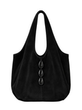 A black suede slouchy shoulder bag with three large black cowrie down the front, set against a solid light gray background.