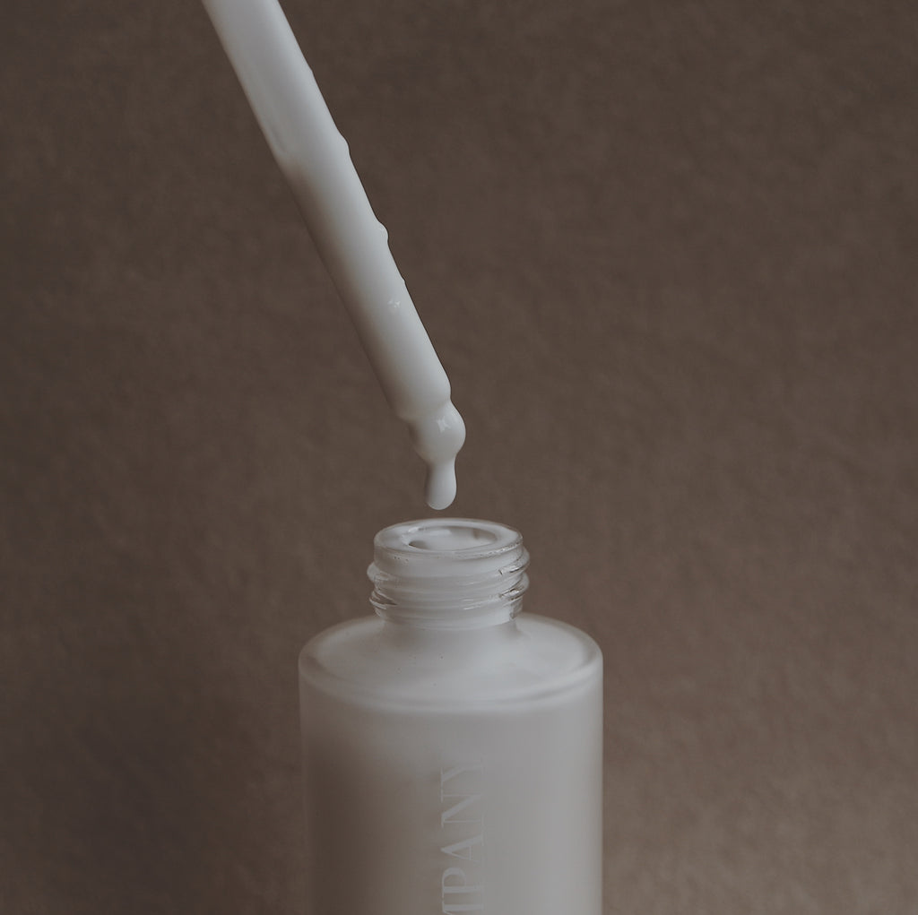 Goat Milk Cleanser White dropper bottle with a dropper on a brown background