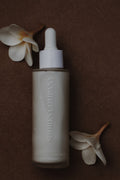 Shores Company Skincare bottle with dropper on a brown background with flowers