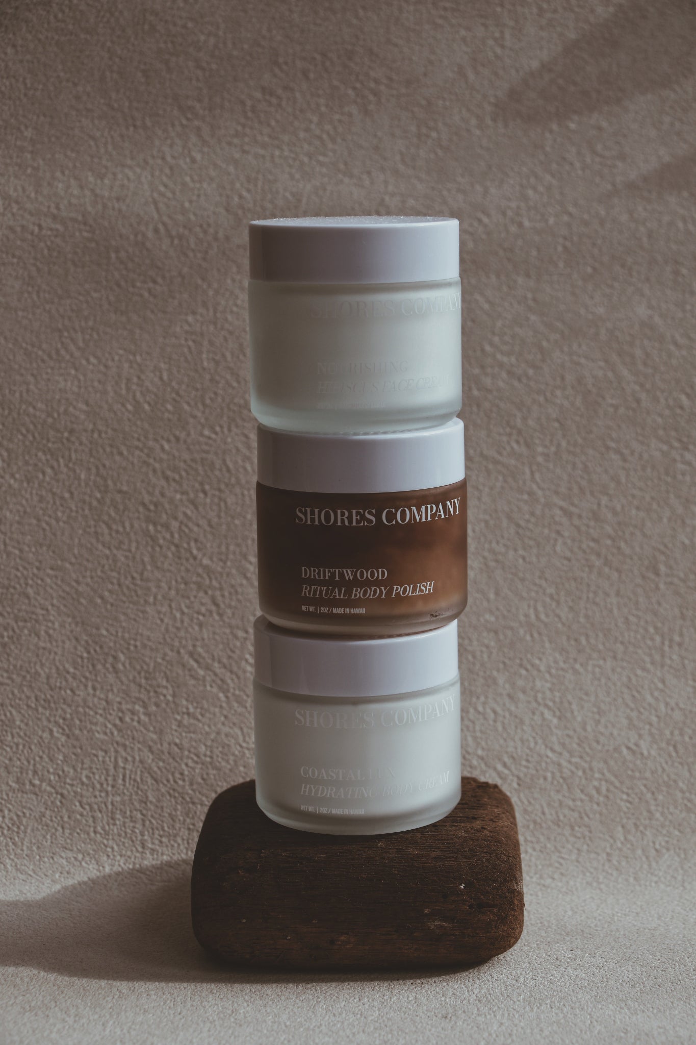 Shores skin care stacked on a wooden block against a neutral background