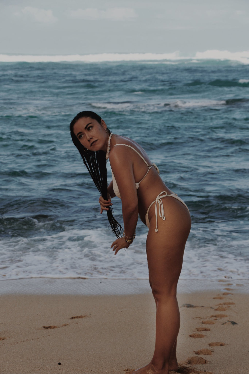 Woman in Vai bikini on a beach with ocean waves in the background