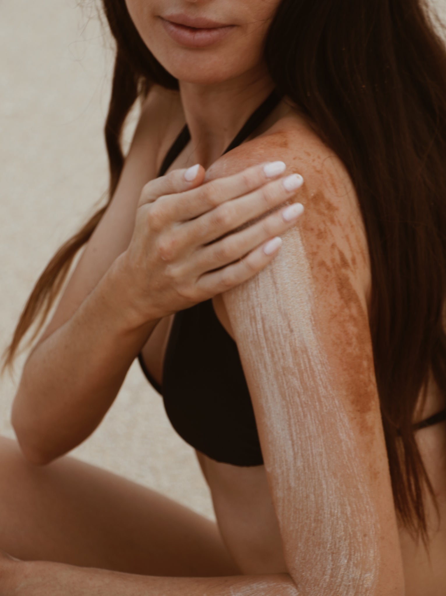 Woman applying Shores Company Driftwood Body Polish to her shoulder for deep exfoliation and skin renewal, made with natural, eco-friendly ingredients.