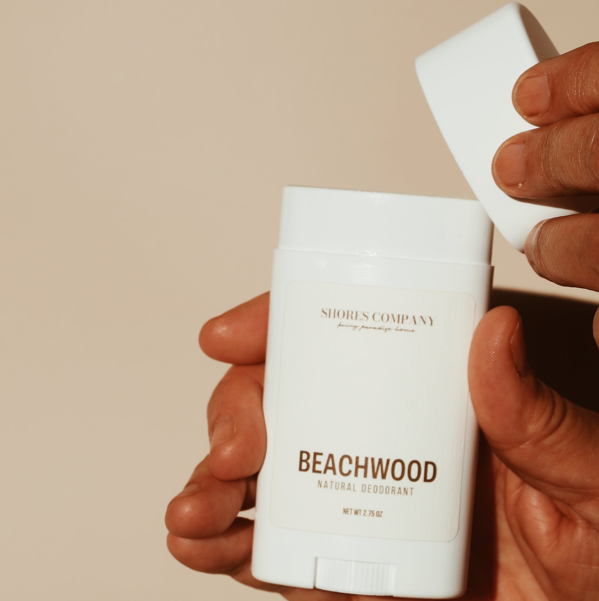 Hand opening the cap of Shores Company Beachwood Natural Deodorant, highlighting its easy application and clean formulation.