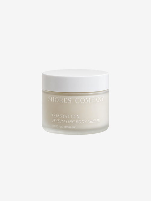 A frosted glass jar of Shores Company Coastal Lux Hydrating Body Creme with a white lid, centered on a light gray background.