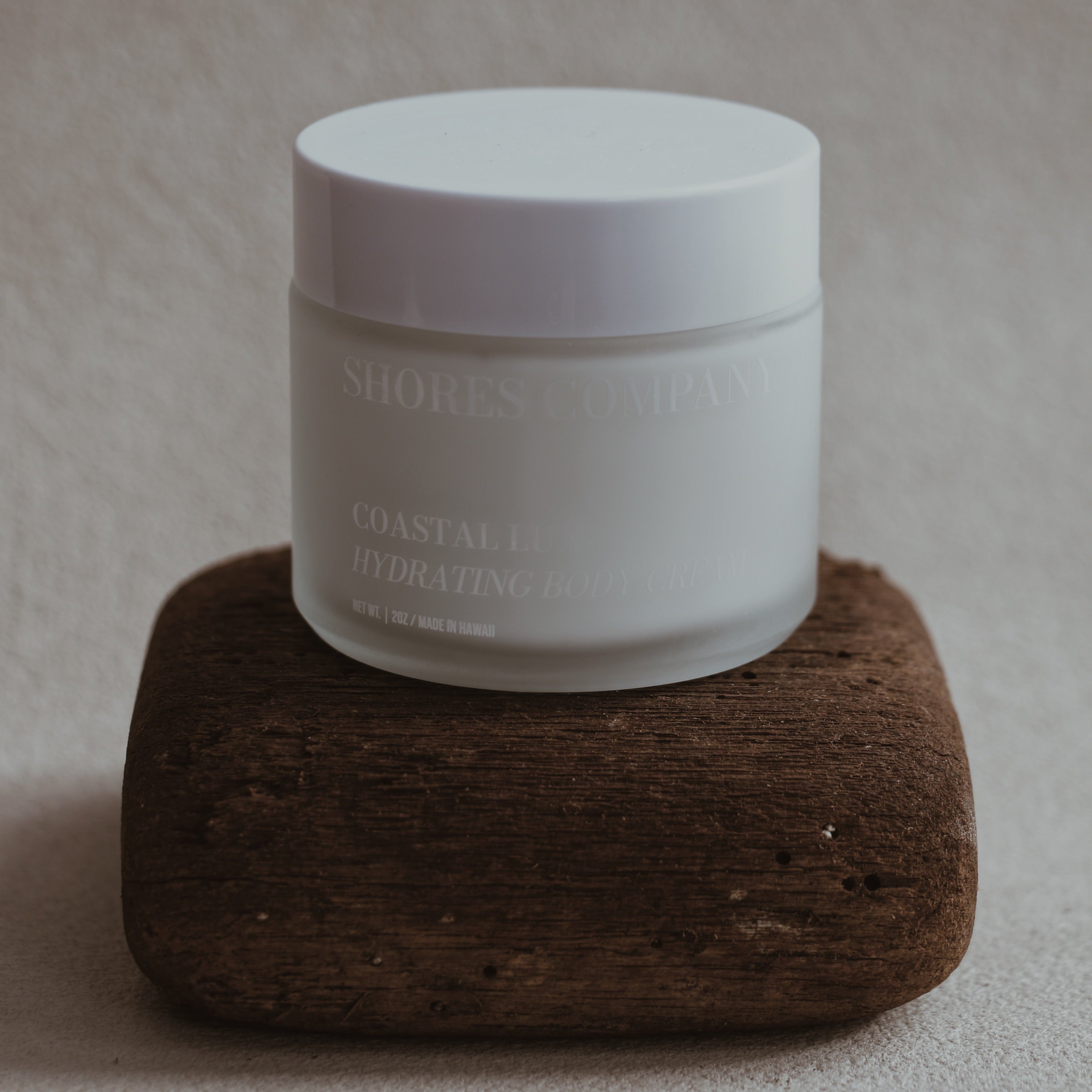 Coast Lux Body Cream jar with a label on a brown wood