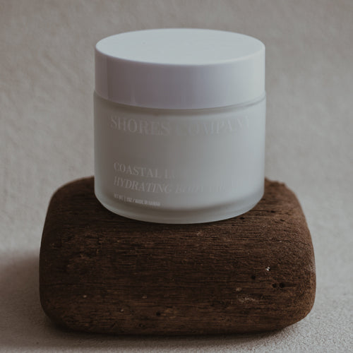 Coast Lux Body Cream jar with a label on a brown wood