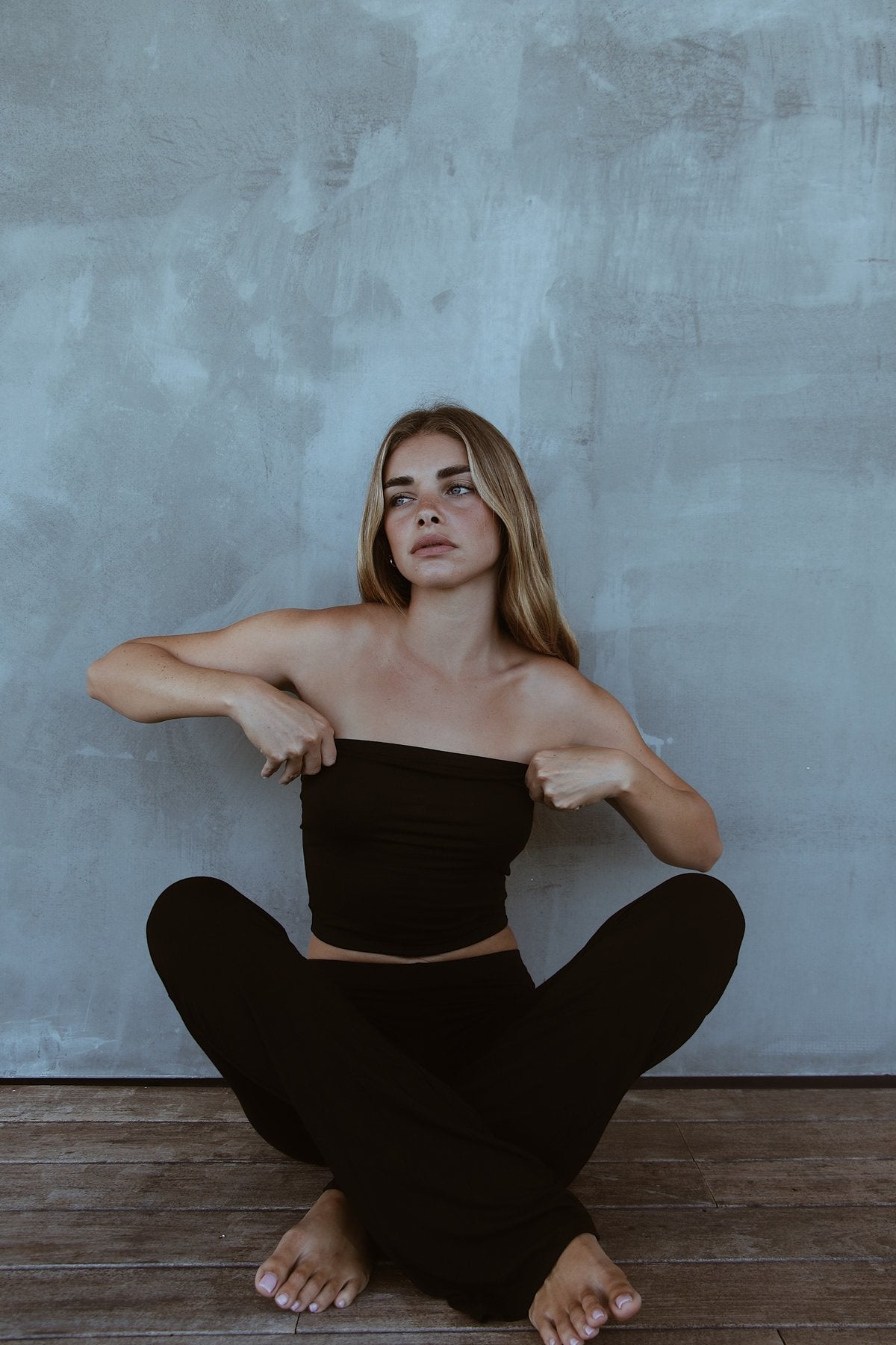 Model seated in the Indah Lounge Pant, styled with a black bandeau top. Relaxed fit with soft bamboo drape.