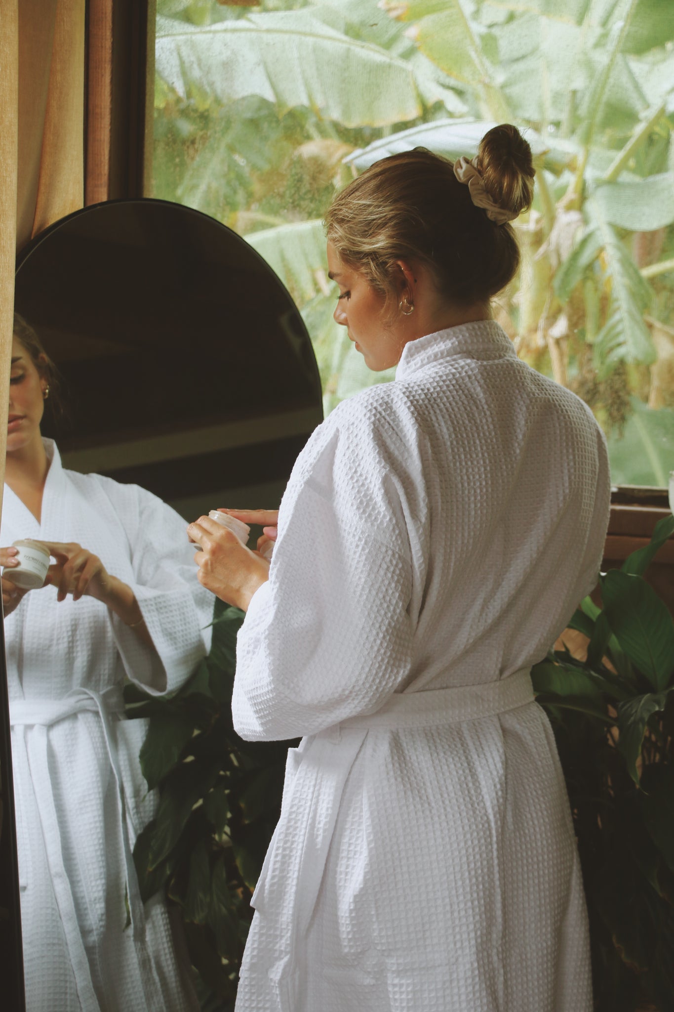 Model standing near a mirror, applying skincare in the Noosa Bathrobe, showcasing its comfort and effortless elegance.