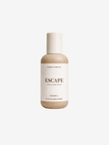 A bottle of SHORES COMPANY ESCAPE Hand & Body Wash in the Pacifica scent, featuring a beige bottle and a cream-colored label and cap, centered on a light gray background.