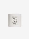 A white ceramic candle jar with a minimalist black-and-white tropical illustration label on the front, reading 'Shores Company' and 'Drifter'.