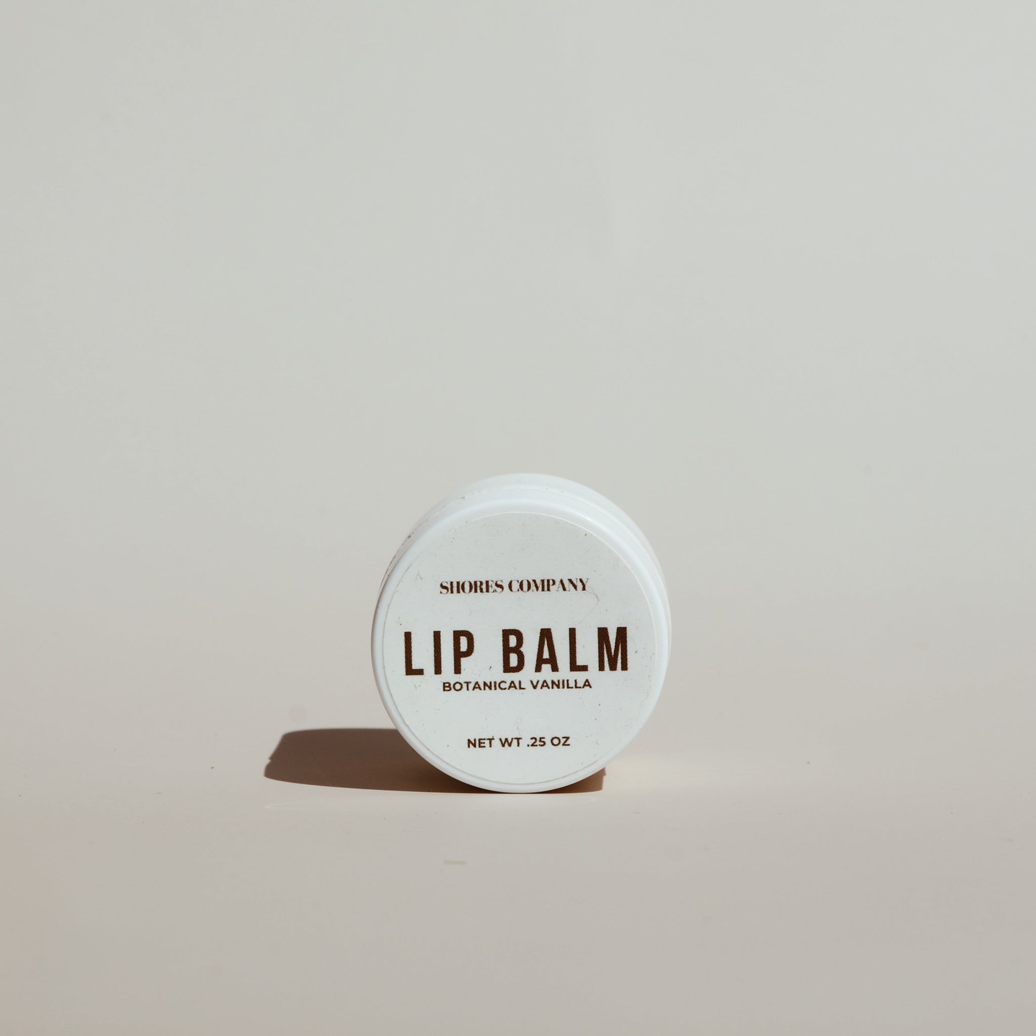 Shores Company Lip Nectar Balm in minimalist packaging, placed on a neutral background with soft lighting.