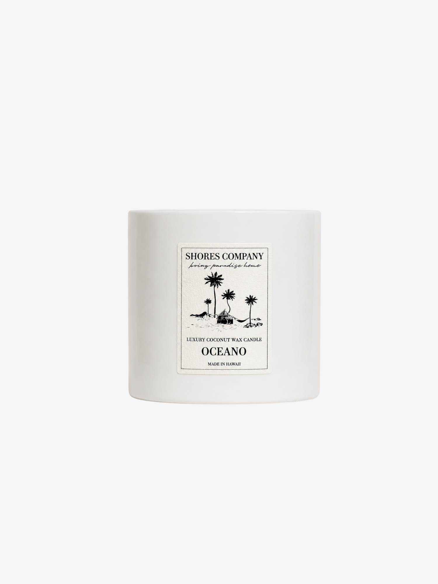 A white ceramic candle jar with a minimalist label from Shores Company, featuring a palm tree illustration and the scent name Oceano, set against a solid white background.