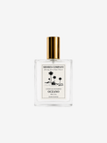 A modern perfume with a clear glass square shape with gold finished metal rod and cap,  against a plain white background.