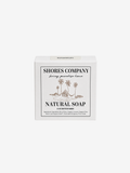 A white rectangular box of Shores Company Natural Soap, featuring a central black-bordered label with a palm tree illustration and the text 'NATURAL SOAP' and 'bring paradise home'.